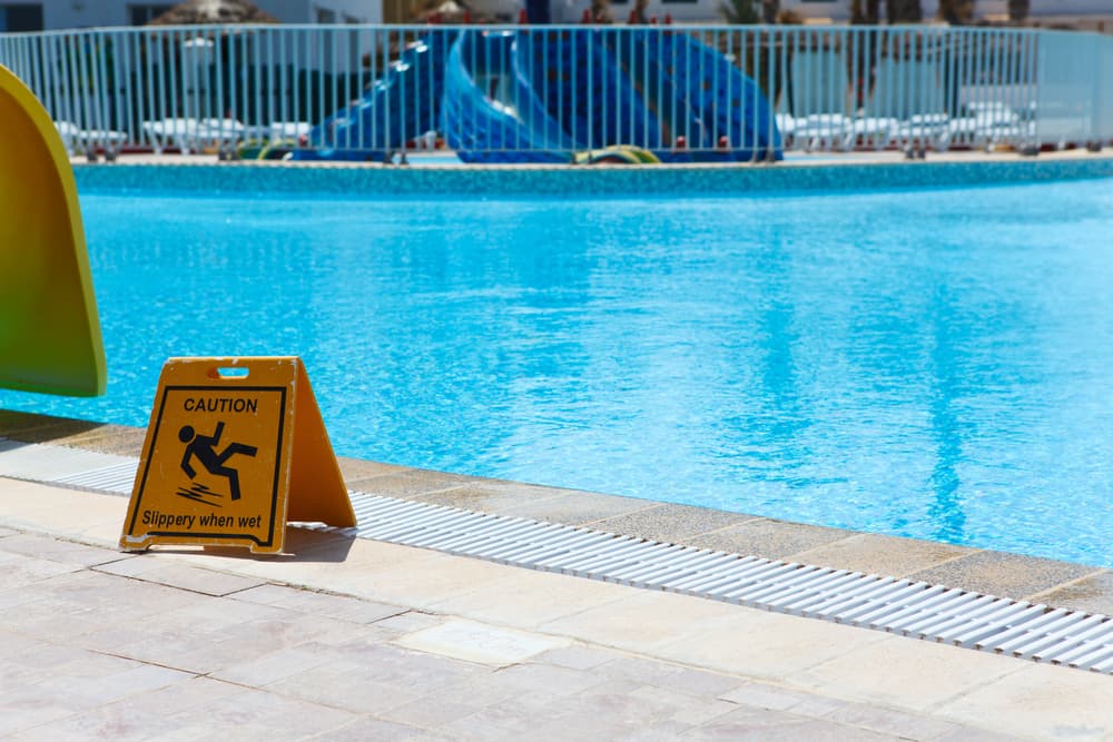 Slippery floor warning sign next to a pool