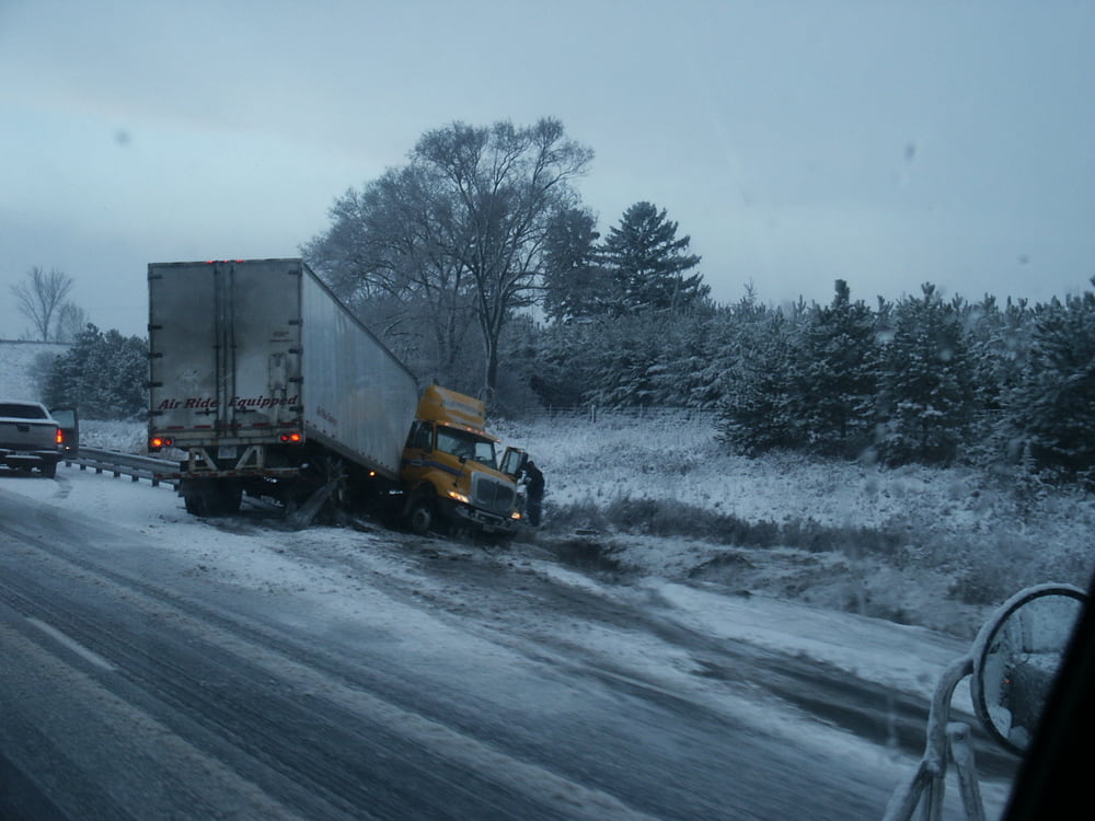 semi-truck jackknifed on side of the road on an overcast winter's day