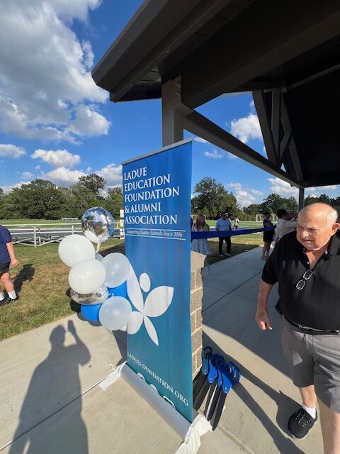 blue banner with white and blue balloons and man walking to the side